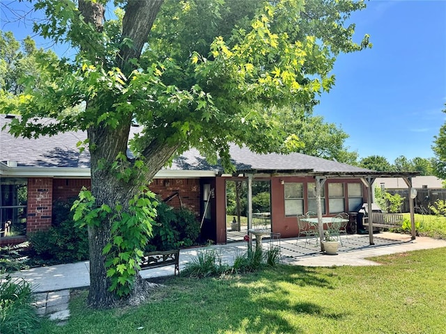 202 Flanders Dr, Chickasha, OK 73018 - rear view of property with a yard, a patio area, brick siding, and roof with shingles
