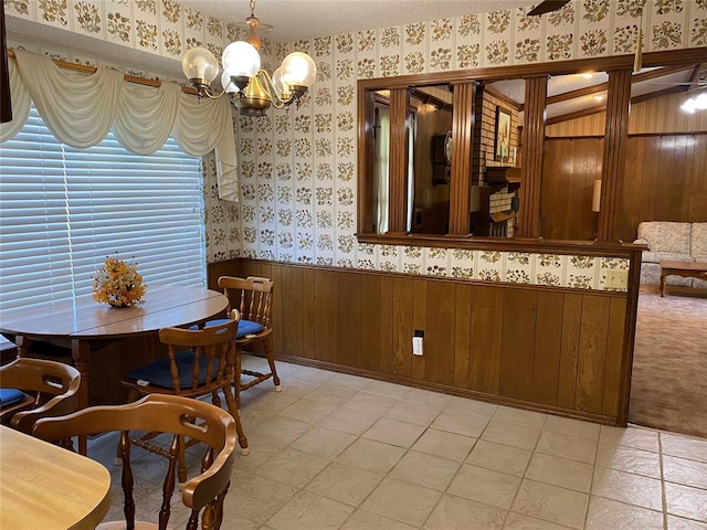 dining area with wallpapered walls, a chandelier, a wainscoted wall, and wooden walls