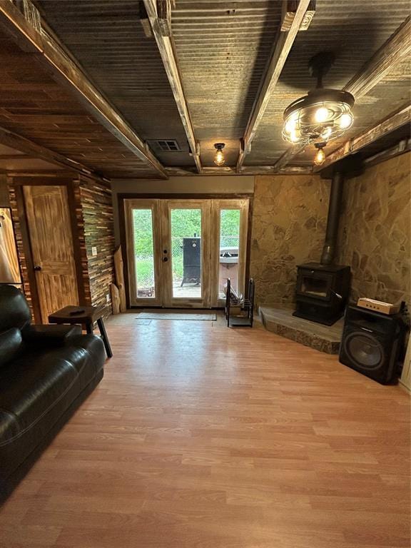 living room with beam ceiling, a wood stove, wood finished floors, and wood ceiling
