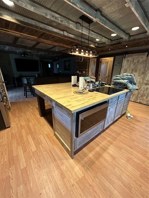 kitchen with wood counters, stainless steel microwave, wood finished floors, and black electric cooktop