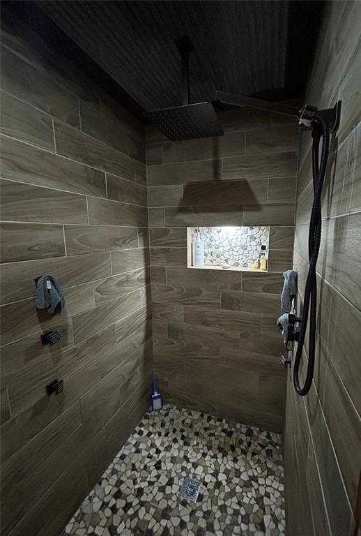 bathroom with tiled shower and tile patterned flooring