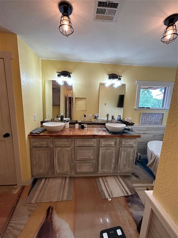 full bath with wood finished floors, double vanity, and a freestanding tub