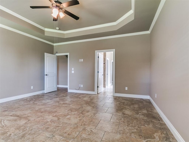 unfurnished room featuring ceiling fan, a tray ceiling, stone finish flooring, baseboards, and crown molding