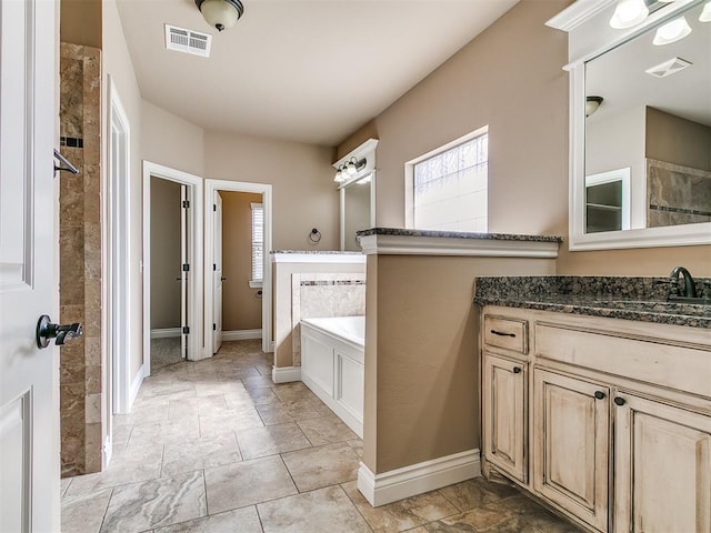 full bath featuring baseboards, a garden tub, vanity, and a tile shower
