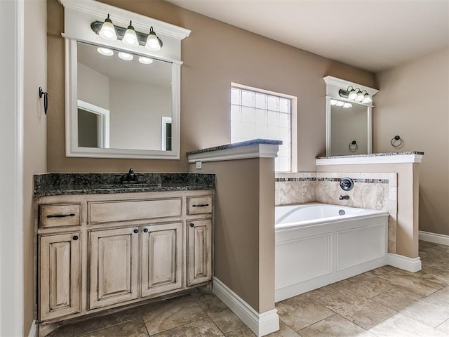 full bathroom with baseboards, a bath, and vanity