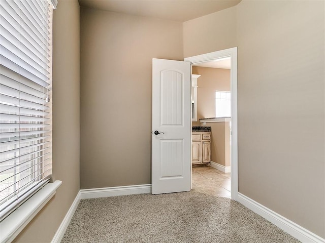 unfurnished room featuring light colored carpet and baseboards