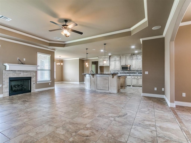 kitchen with a raised ceiling, open floor plan, stainless steel microwave, ceiling fan, and a kitchen bar