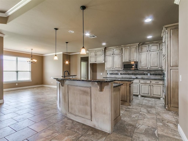 kitchen featuring stainless steel microwave, baseboards, a center island with sink, ornamental molding, and a breakfast bar area