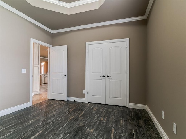 unfurnished bedroom featuring ornamental molding, wood finished floors, baseboards, and a closet