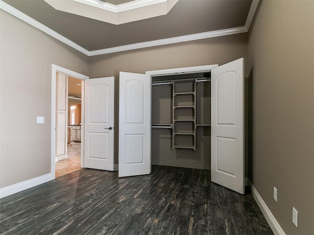 unfurnished bedroom featuring ornamental molding, wood finished floors, a closet, and baseboards