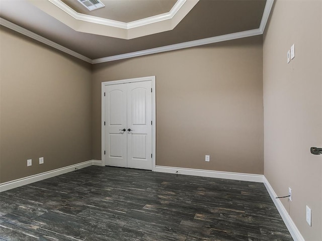 spare room with a tray ceiling, wood finished floors, crown molding, and baseboards
