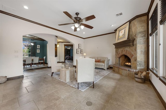 1401 Canyon Bridge Ln, Edmond, OK 73034 - living room featuring crown molding, baseboards, a ceiling fan, a stone fireplace, and a chandelier
