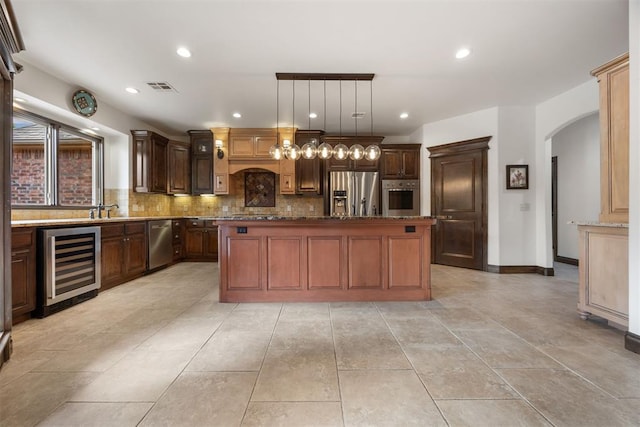 1401 Canyon Bridge Ln, Edmond, OK 73034 - kitchen with beverage cooler, appliances with stainless steel finishes, arched walkways, tasteful backsplash, and recessed lighting