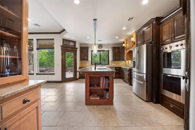 1401 Canyon Bridge Ln, Edmond, OK 73034 - kitchen featuring appliances with stainless steel finishes, light stone counters, backsplash, a kitchen island with sink, and recessed lighting