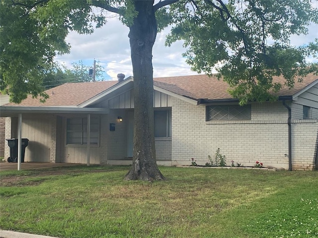 view of front of home with brick siding, roof with shingles, and a front yard