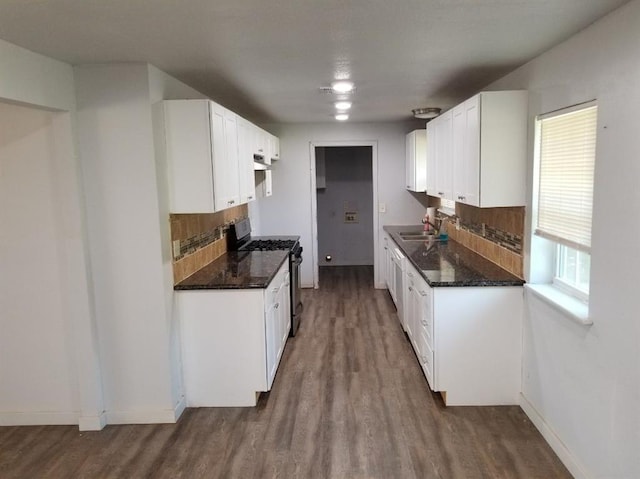 kitchen with gas range oven, dark wood-type flooring, tasteful backsplash, and white cabinetry
