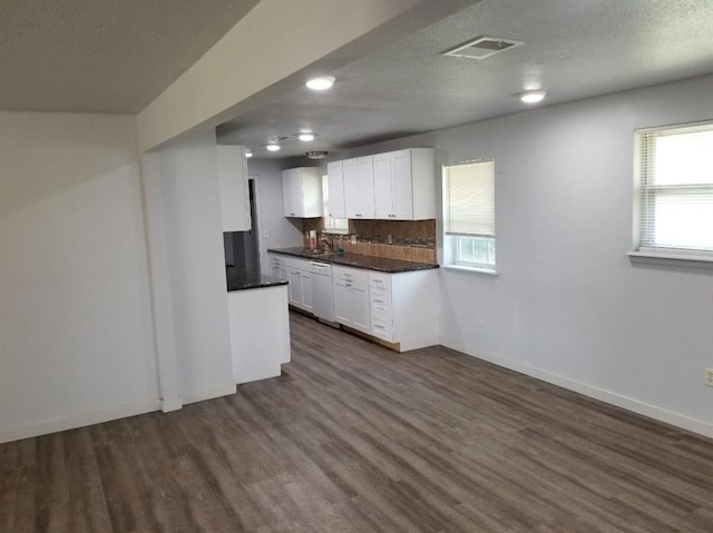 kitchen featuring white dishwasher, dark countertops, dark wood-style floors, white cabinetry, and baseboards