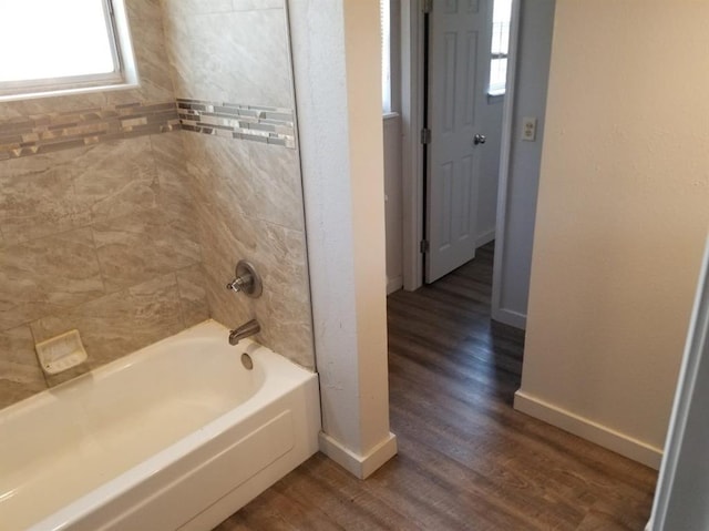 bathroom with wood finished floors, baseboards, and washtub / shower combination