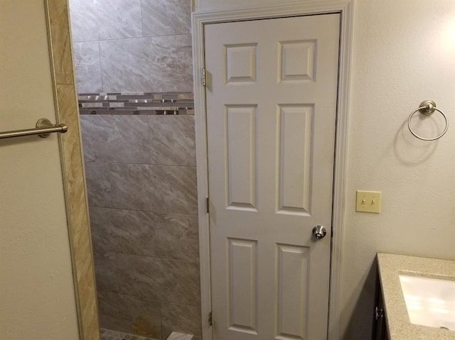 bathroom with tiled shower and a sink