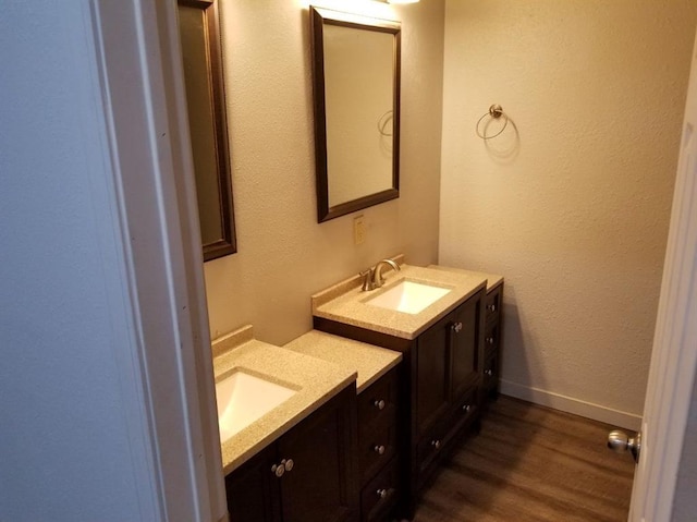 bathroom with wood finished floors and two vanities