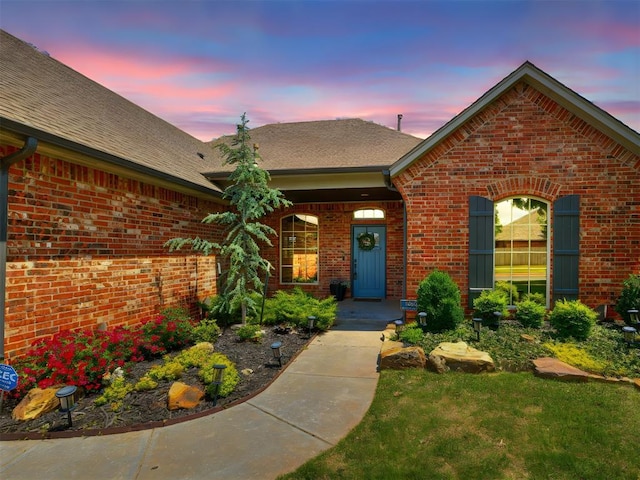 view of front of property featuring roof with shingles and brick siding