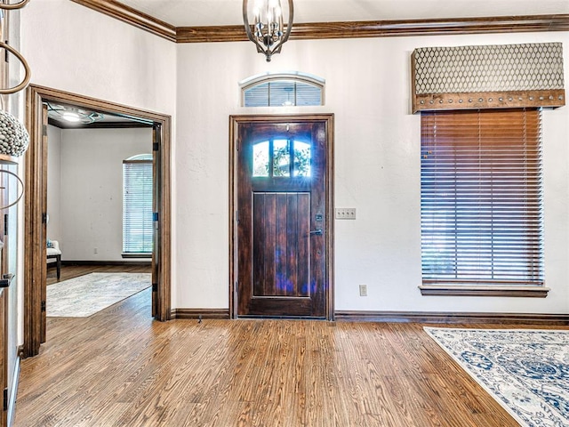 entryway with crown molding, wood finished floors, and baseboards