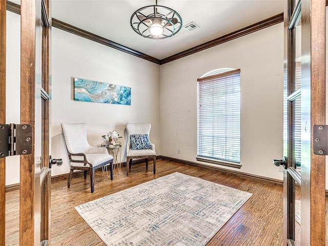 living area featuring ornamental molding, healthy amount of natural light, baseboards, and wood finished floors