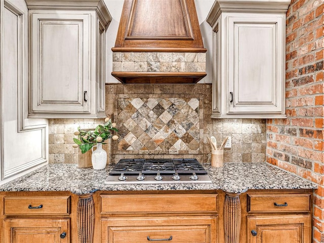 kitchen featuring premium range hood, stainless steel gas cooktop, and backsplash