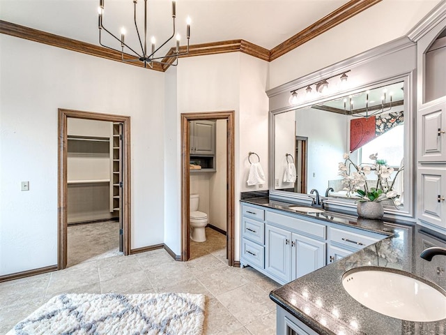 bathroom featuring a chandelier, ornamental molding, toilet, vanity, and a spacious closet