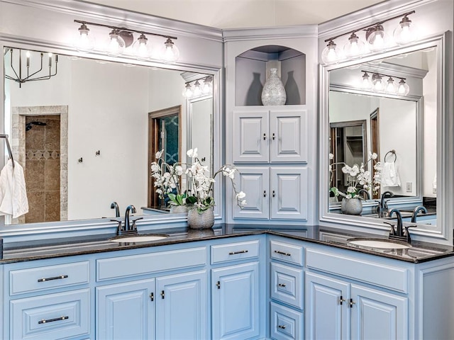 bathroom with double vanity, crown molding, and a tile shower