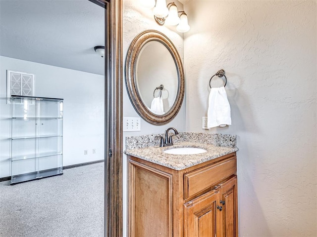 bathroom with vanity, a textured wall, and baseboards
