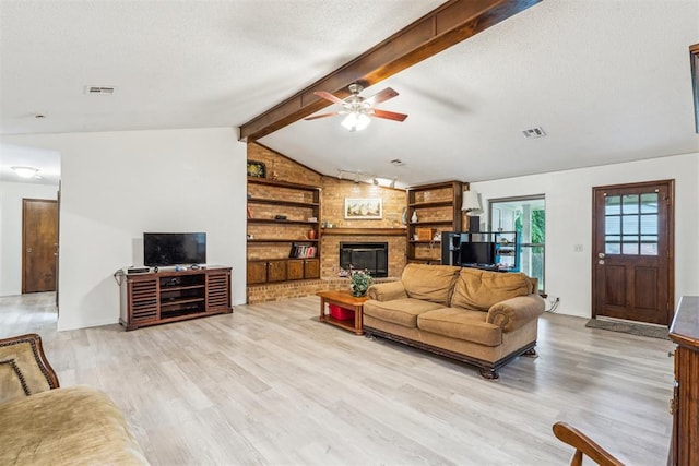 living room featuring light wood-type flooring, a fireplace, a ceiling fan, and a textured ceiling