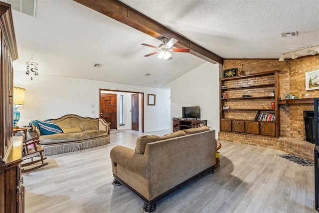 living area with light wood finished floors, a fireplace, ceiling fan, a textured ceiling, and track lighting