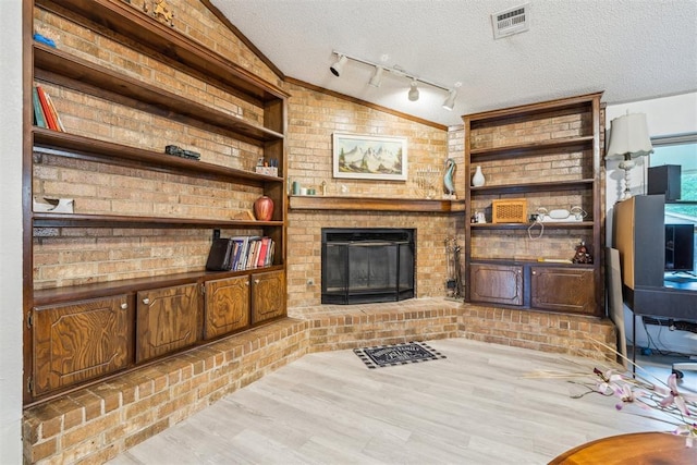 living area featuring a textured ceiling, wood finished floors, a fireplace, and built in features