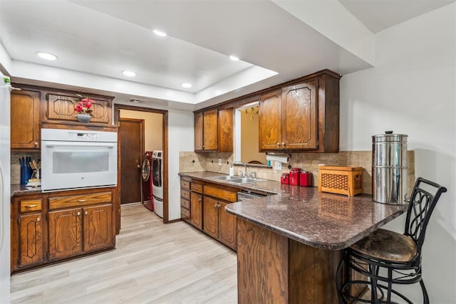 kitchen with white oven, a sink, independent washer and dryer, tasteful backsplash, and recessed lighting