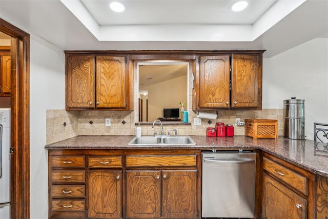 kitchen featuring dishwasher, a sink, tasteful backsplash, and dark countertops