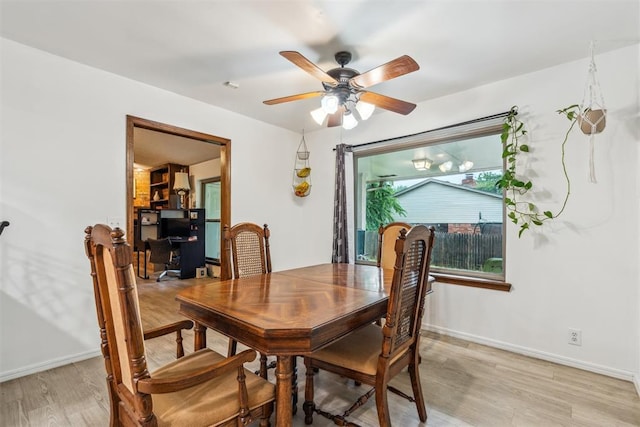 dining room featuring light wood finished floors, ceiling fan, and baseboards