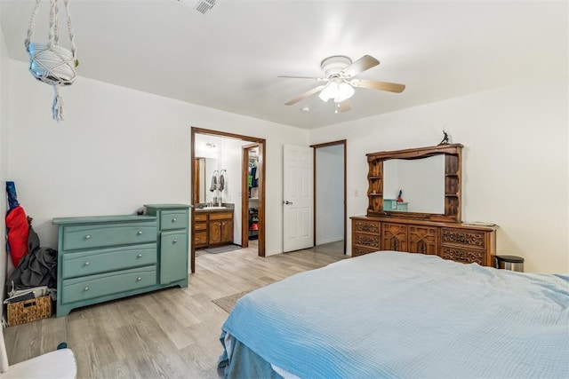 bedroom with light wood finished floors, a ceiling fan, and ensuite bath