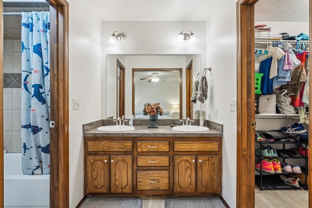 full bathroom featuring double vanity, a ceiling fan, shower / tub combo, a spacious closet, and wood finished floors