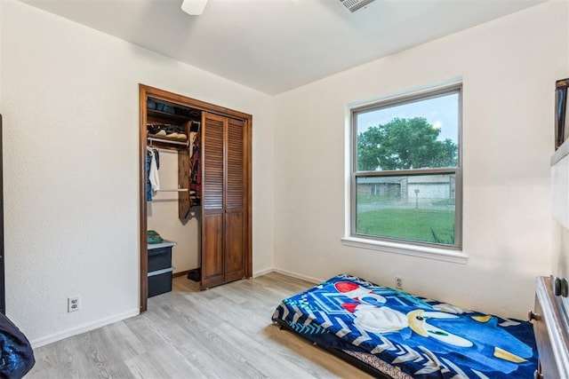 bedroom with light wood-style flooring, a closet, and baseboards
