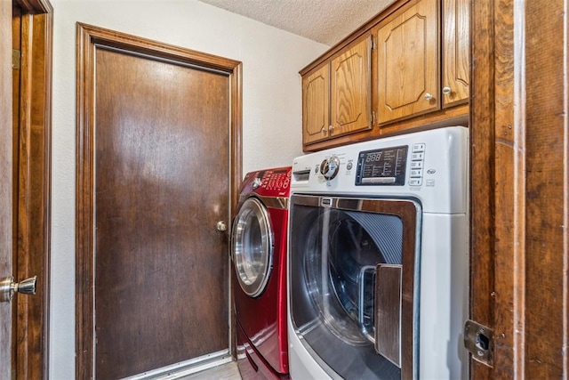 washroom featuring separate washer and dryer, cabinet space, and a textured ceiling