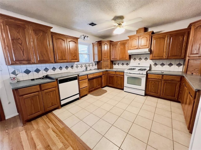 36040 E 1140th Rd Unit 114Rd, Seminole, OK 74868 - kitchen with white appliances, brown cabinetry, under cabinet range hood, a sink, and a textured ceiling
