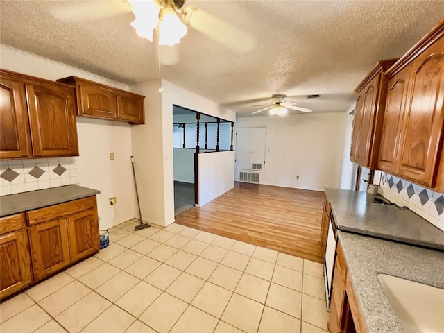 36040 E 1140th Rd Unit 114Rd, Seminole, OK 74868 - kitchen with ceiling fan, brown cabinets, light tile patterned flooring, a textured ceiling, and tasteful backsplash
