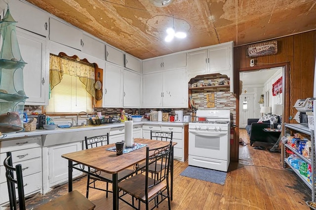 kitchen with white gas stove, light countertops, light wood-style floors, and white cabinets