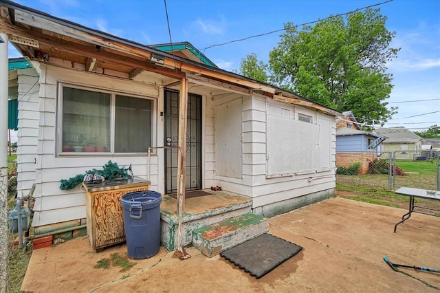 view of exterior entry with fence and a patio