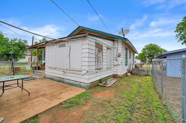 view of side of home featuring fence, a gate, and a patio