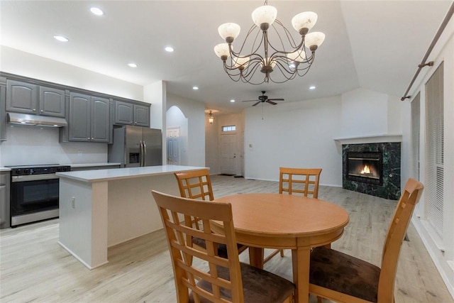 dining room with a high end fireplace, light wood-type flooring, arched walkways, a chandelier, and recessed lighting