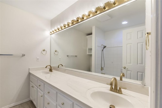 bathroom featuring tiled shower and double vanity