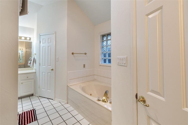 bathroom featuring tile patterned floors, vaulted ceiling, a tub with jets, vanity, and baseboards