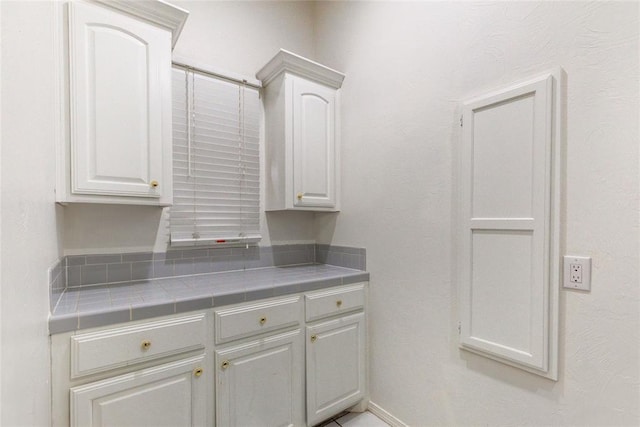 kitchen featuring tile countertops and white cabinets